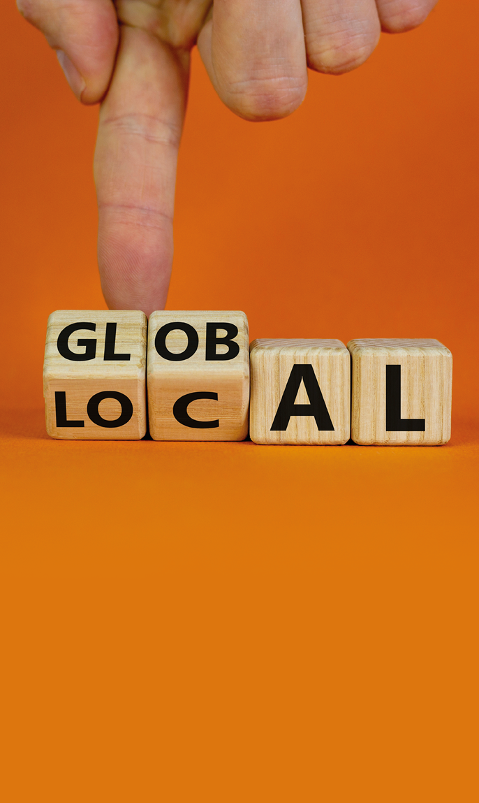 Local or global symbol  Hand turns cubes and changes the word 'local' to 'global'  Beautiful orange background  Business and local or global concept  Copy space 