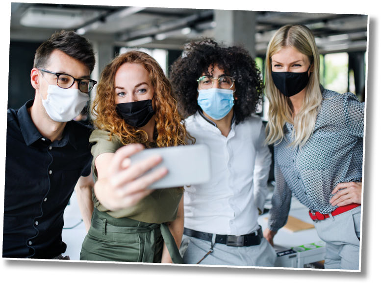 Young people with face masks back at work in office after lockdown, taking selfie 