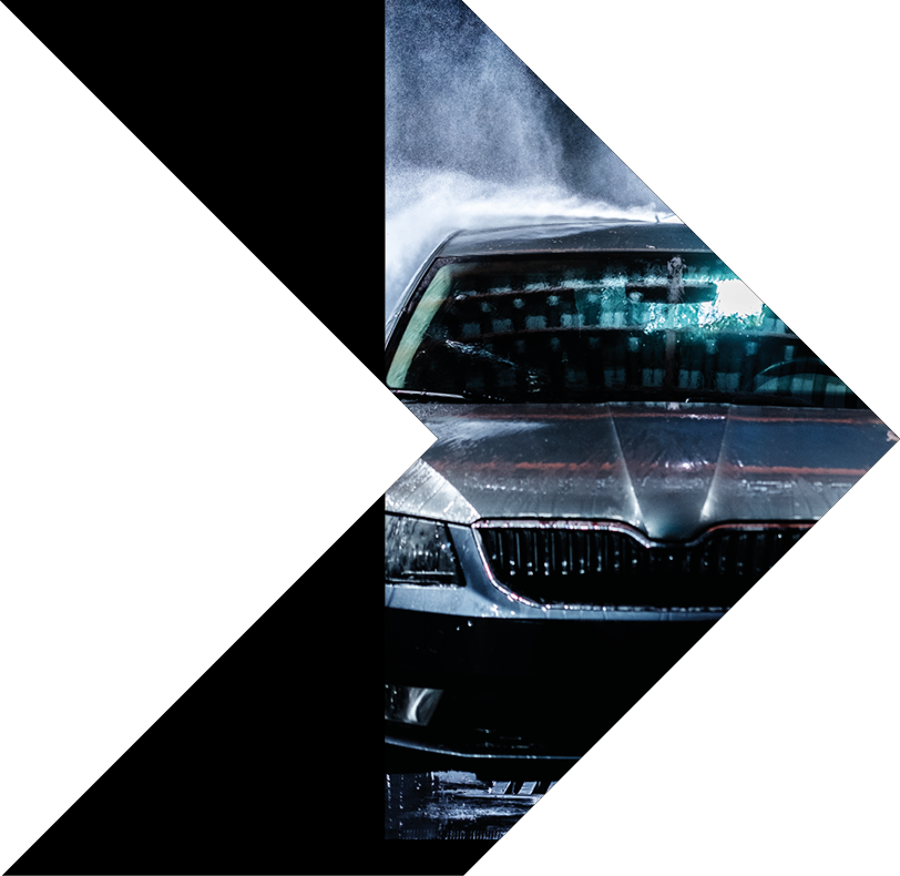 A man with a beard washes a gray car with a high-pressure washer at night in a car wash  Expensive advertising photography