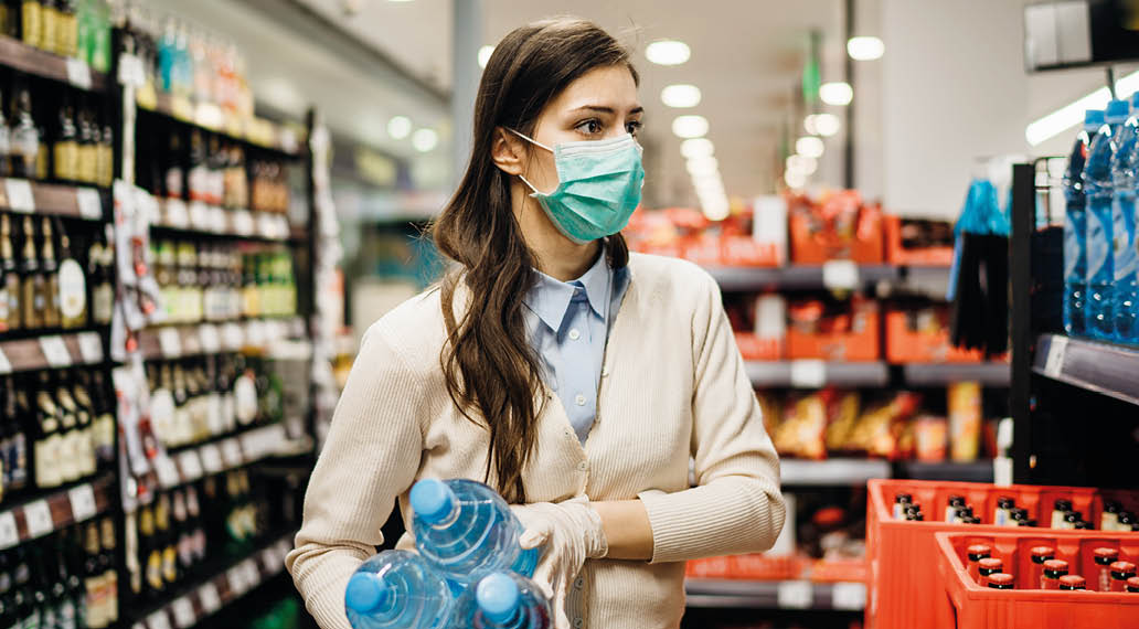 Woman with mask safely shopping for groceries amid the coronavirus pandemic in a stocked grocery store COVID-19 food buying in supermarket Panic buying,stockpiling Lockdown preparation Water shortage