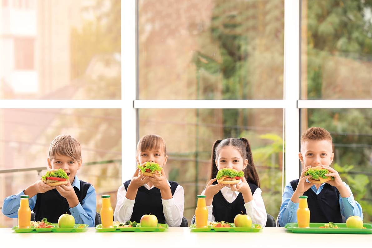 Happy children eating healthy food for lunch in school canteen