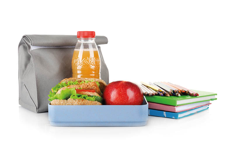 Lunch box and bag with food and stationery on white background