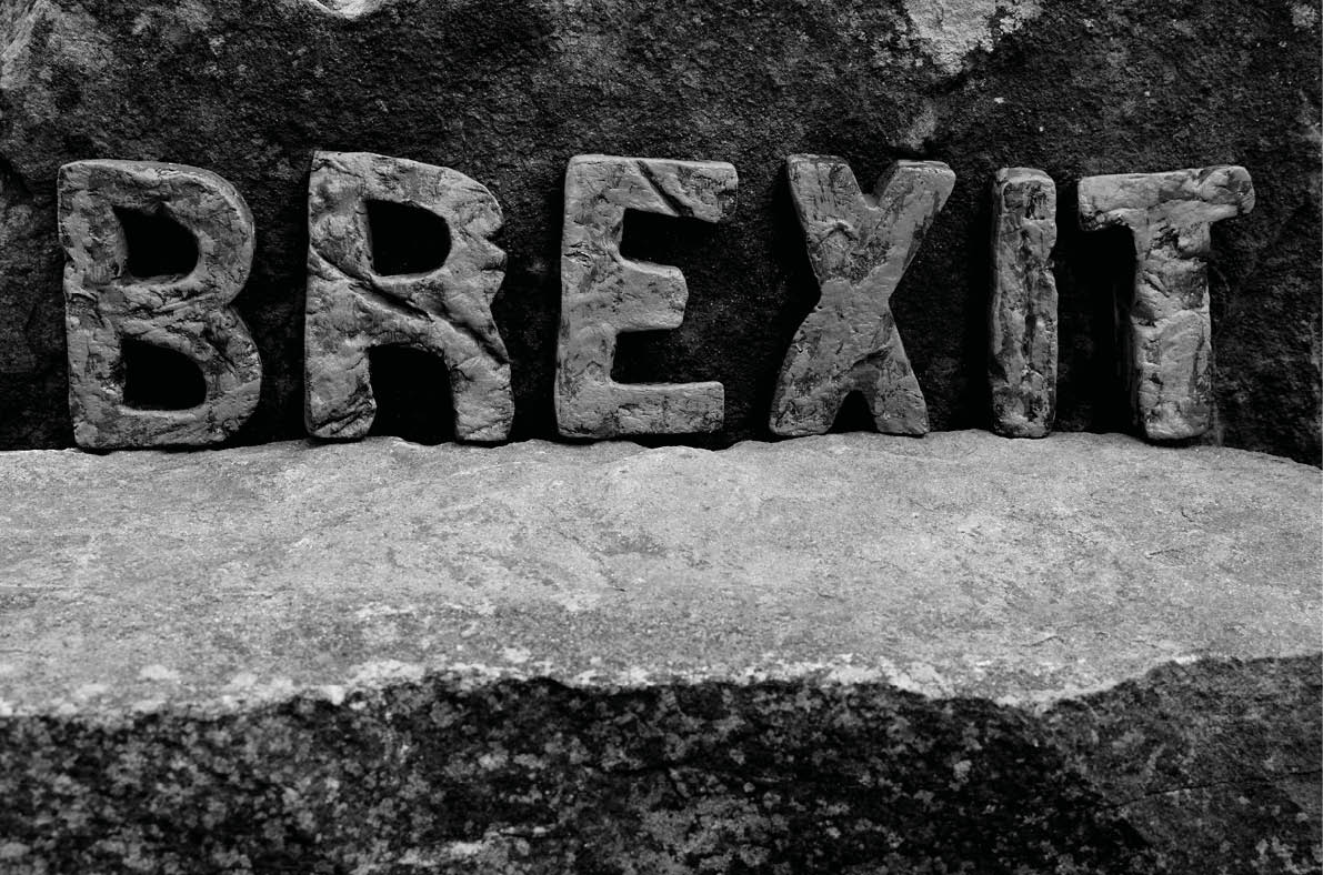 The Word  Brexit  on the Rocks, Showing the Rough Texture of the Letters on a Light Natural Stone Shelf 