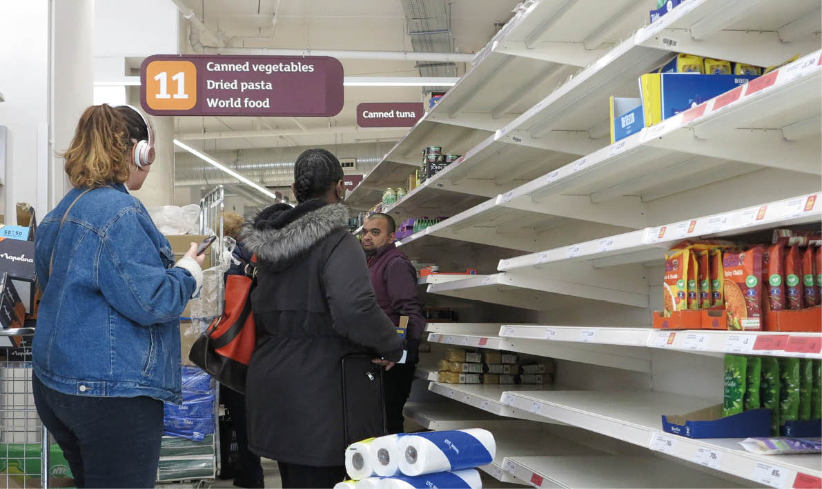 London, England - March 16 2020 - A woman with toilet paper in her basket standing beside empty shelves in a supermarket   Customers stocked up on food and toilet paper during the Covid-19 crisis   
