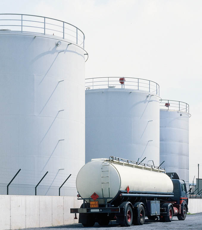 road tanker in front of oil refinery tanks, neutral with copy space
