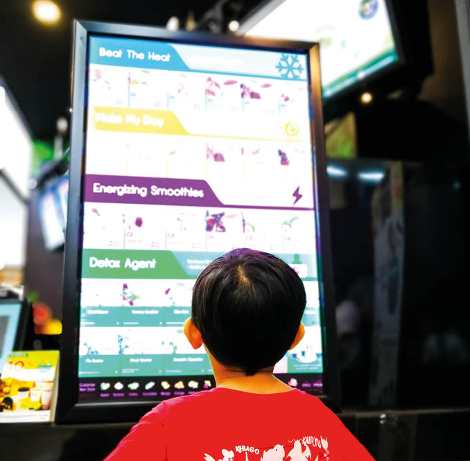 Selangor, Malaysia - March 24, 2018: Little boy is looking at the screen menu in a juice bar at The School, Petaling Jaya 