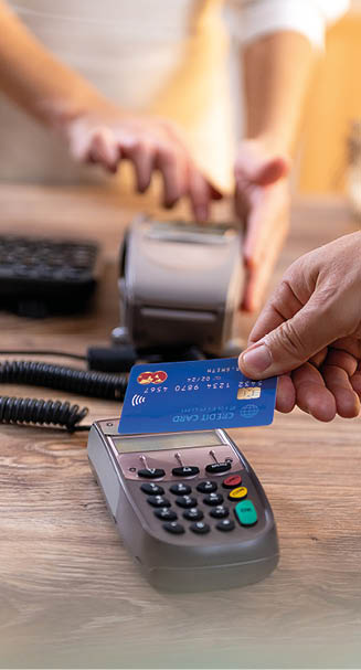 Closeup of Caucasian right hand, holding a blue credit card and paying at the POS terminal