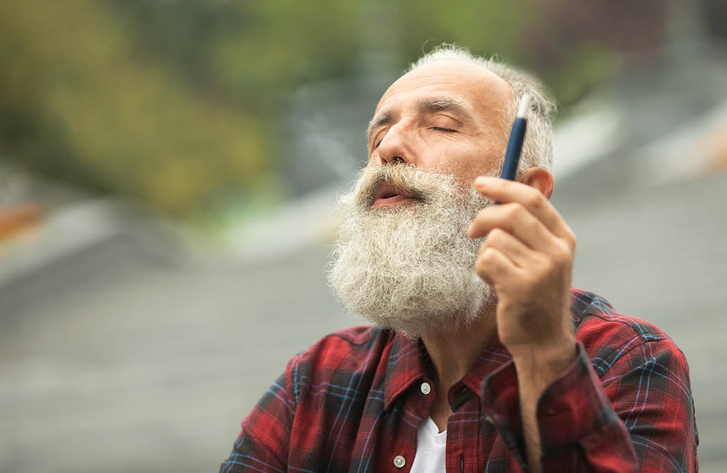 Senior man with beard breathe out smoke  Smoking electronic cigarette  Stress relief concept  Smoking device  Man long beard relaxed with smoking habit  Bearded man vaping  IQOS 