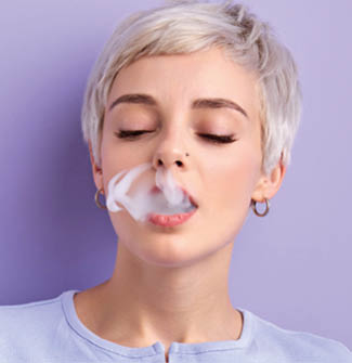 Short haired stylish woman smoking vape isolated on purple background. Vapor concept
