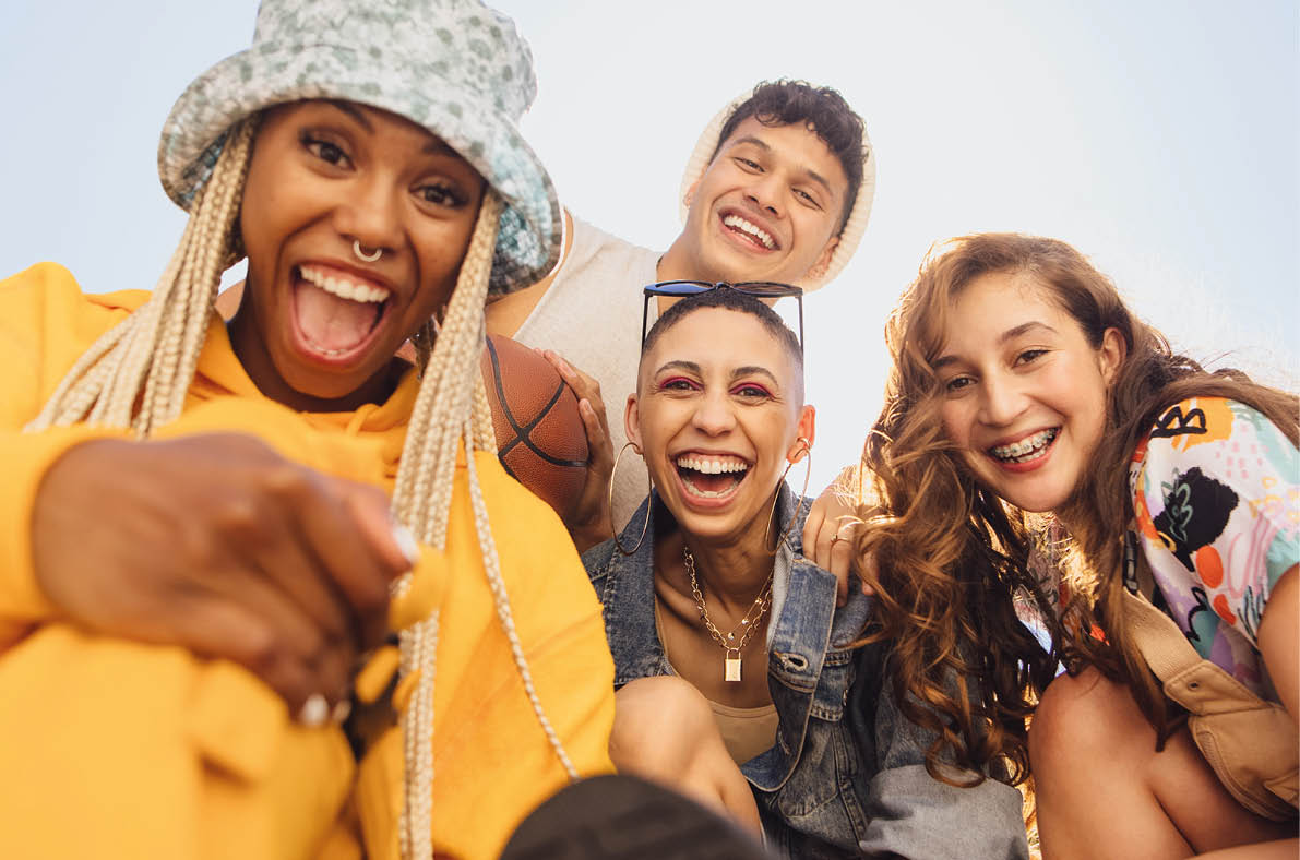 Cheerful generation z friends having fun together outdoors. Group of multiethnic friends smiling at the camera cheerfully. Vibrant young people making happy memories together.