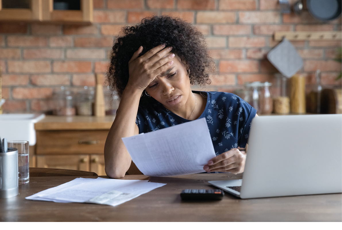 Stressed young african american woman looking at paper bills, feeling confused of high payment rates, having financial problems while summarizing household utilities, bankruptcy lack of money concept.
