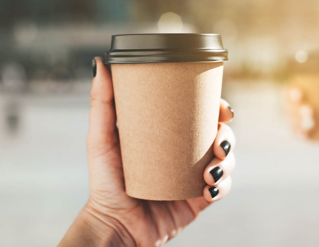 Two paper coffee cups in women's hands with perfect manicure.
