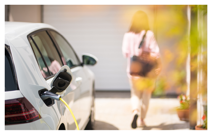Close up of a electric car charger with female silhouette in the background