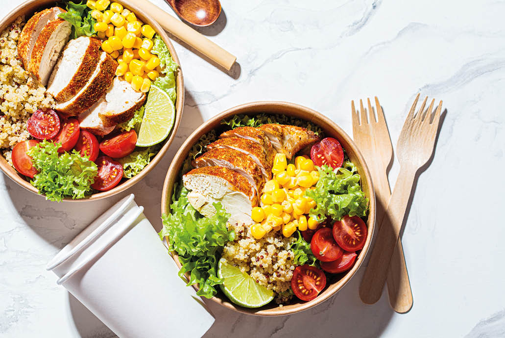 Chicken and quinoa salad with corn and tomatoes in a craft eco bowl, top view. Zero waste, to go food, recycling packaging, eco friendly concept.