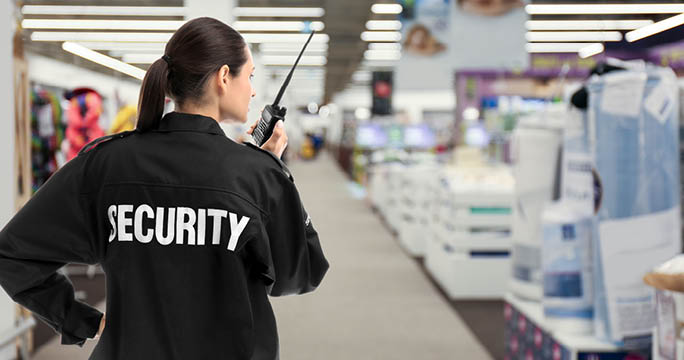 Security guard using portable radio transmitter in shopping mall, space for text