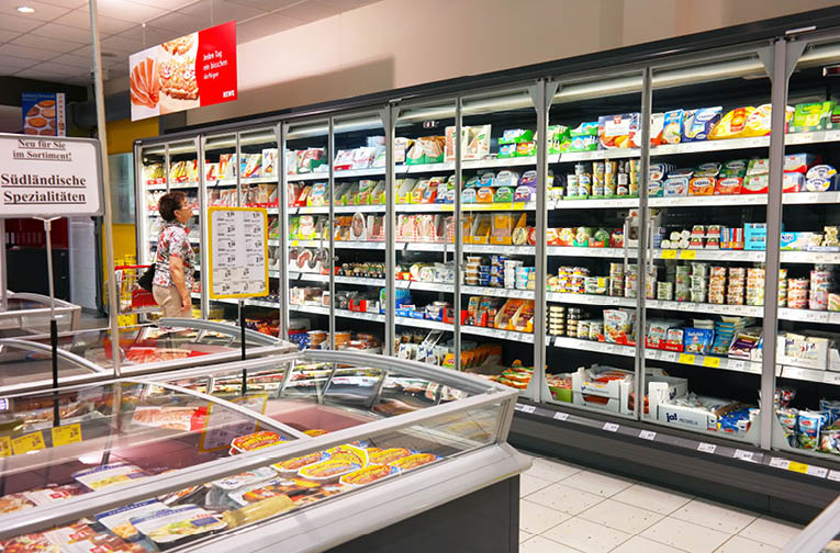 WALDFEUCHT, GERMANY - MAY 11, 2016 : Woman shopping in the refrigerated fresh products aisle of an REWE supermarket, a part of the REWE Group, a German diversified retail and tourism group 