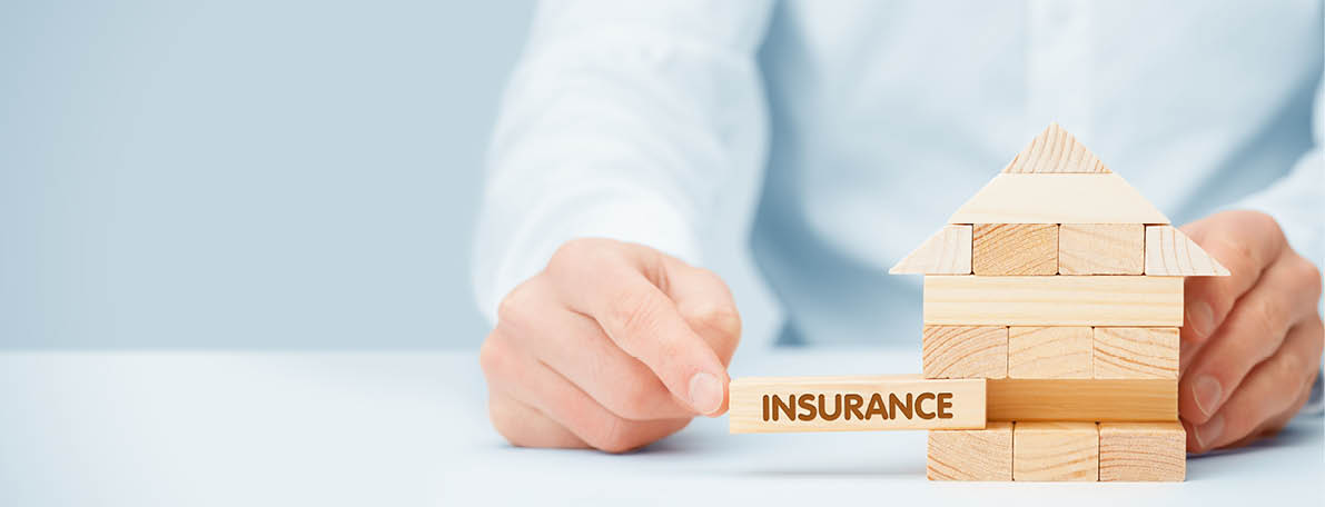 Property (family house) insurance protection concept  Insurance agent complete wooden model of the house with last piece with text insurance 