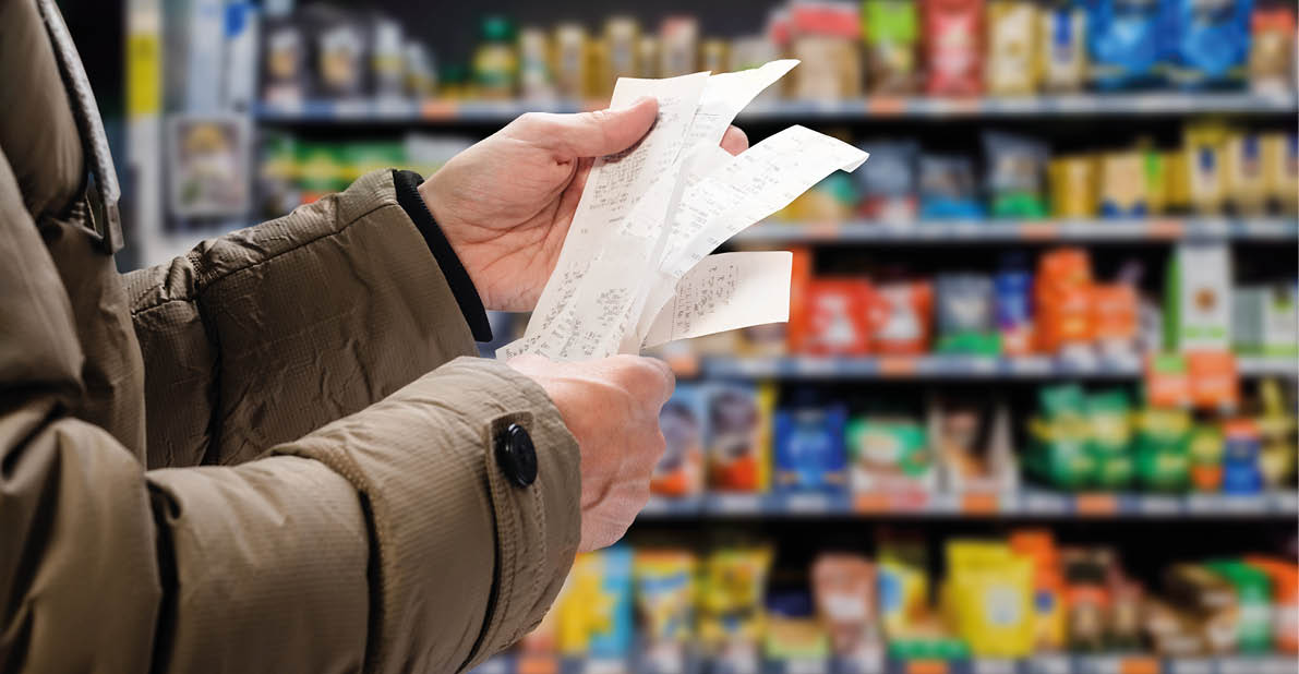 Minded man viewing receipts in supermarket and tracking prices