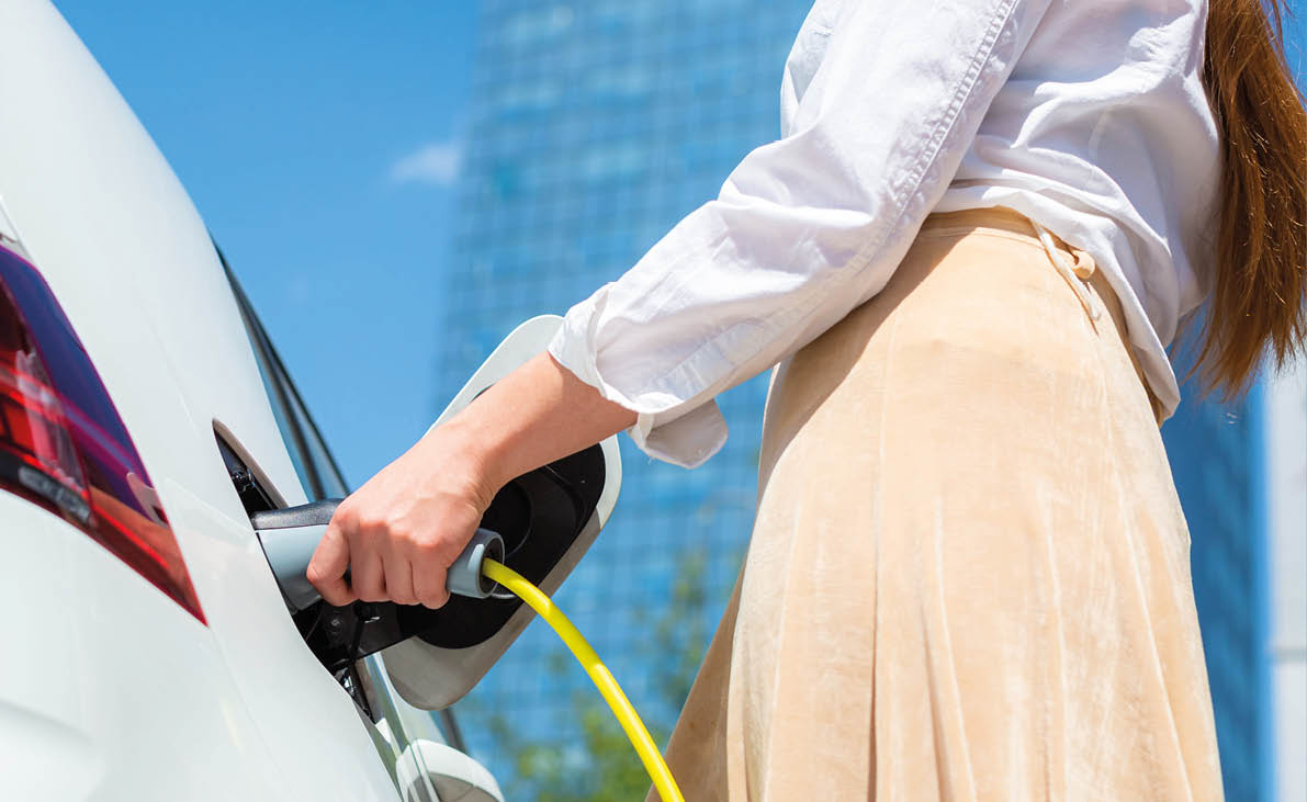 Woman unplugging the electric car charger at a downtown charging point