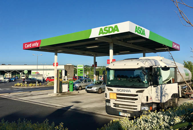Gorseinon, UK: June 27, 2018: A self-service petrol station at an Asda supermarket  A Scania delivery truck is off-loading its fuel to the underground storage tanks  Asda is owned by Wal-mart 