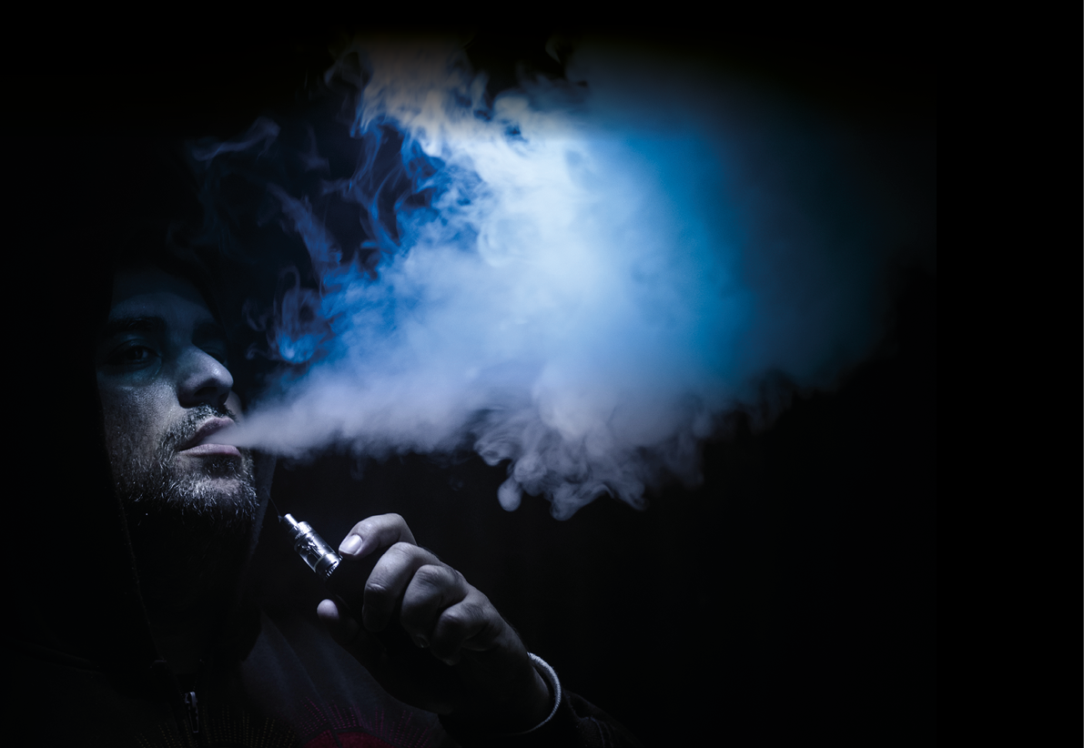 Vaping man holding a mod  A cloud of vapor  Black background  Vaping an electronic cigarette with a lot of smoke  Vape concept