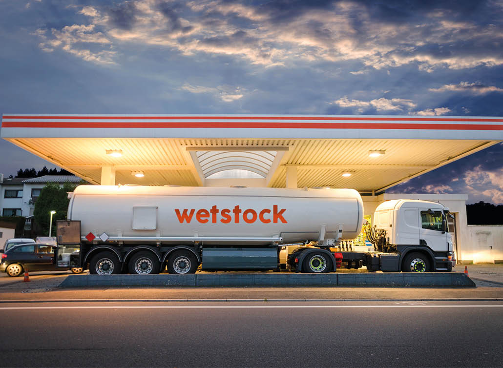 Tanker gas truck delivering fuel at service station against dramatic night sky