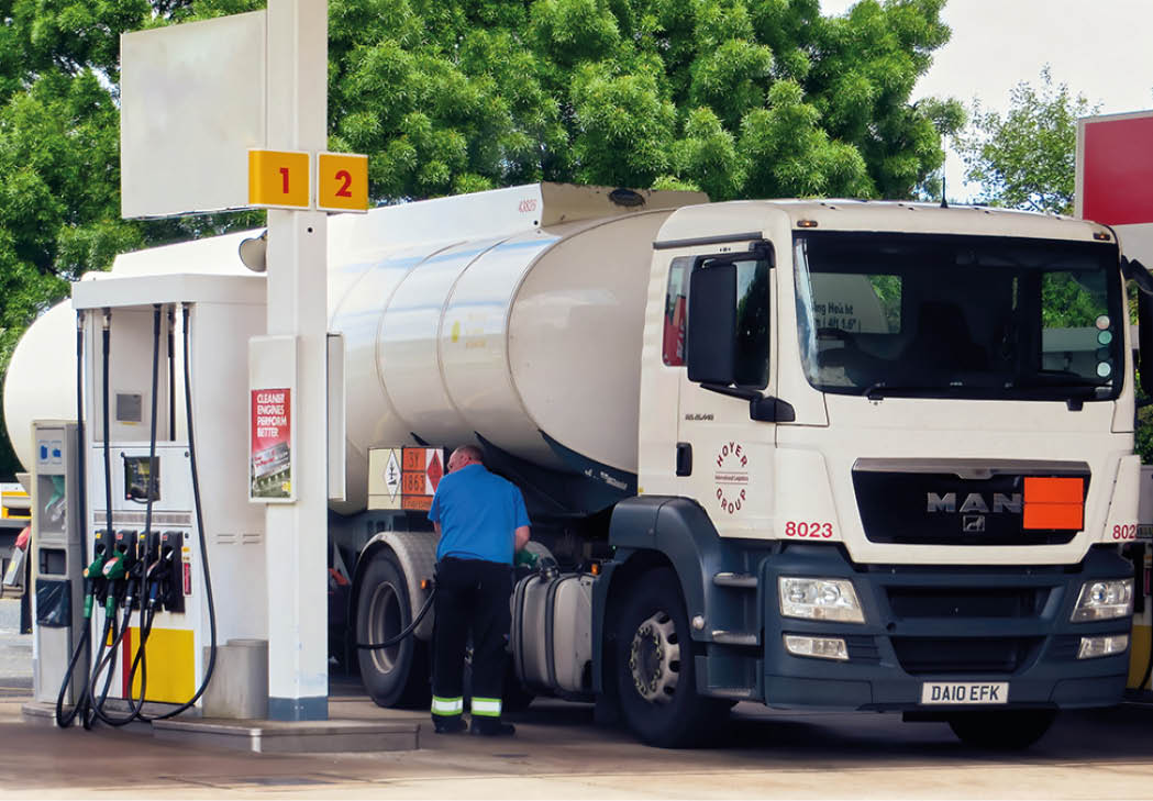 Fuel Tanker Truck Driver Getting Petrol for His Huge Vehicle at Small Gas Station Before Resuming March Toward Airport to Deliver Special Aviation Fuel (1863 Code on Orange Plate). CHEAM, UK -MAY 2015
