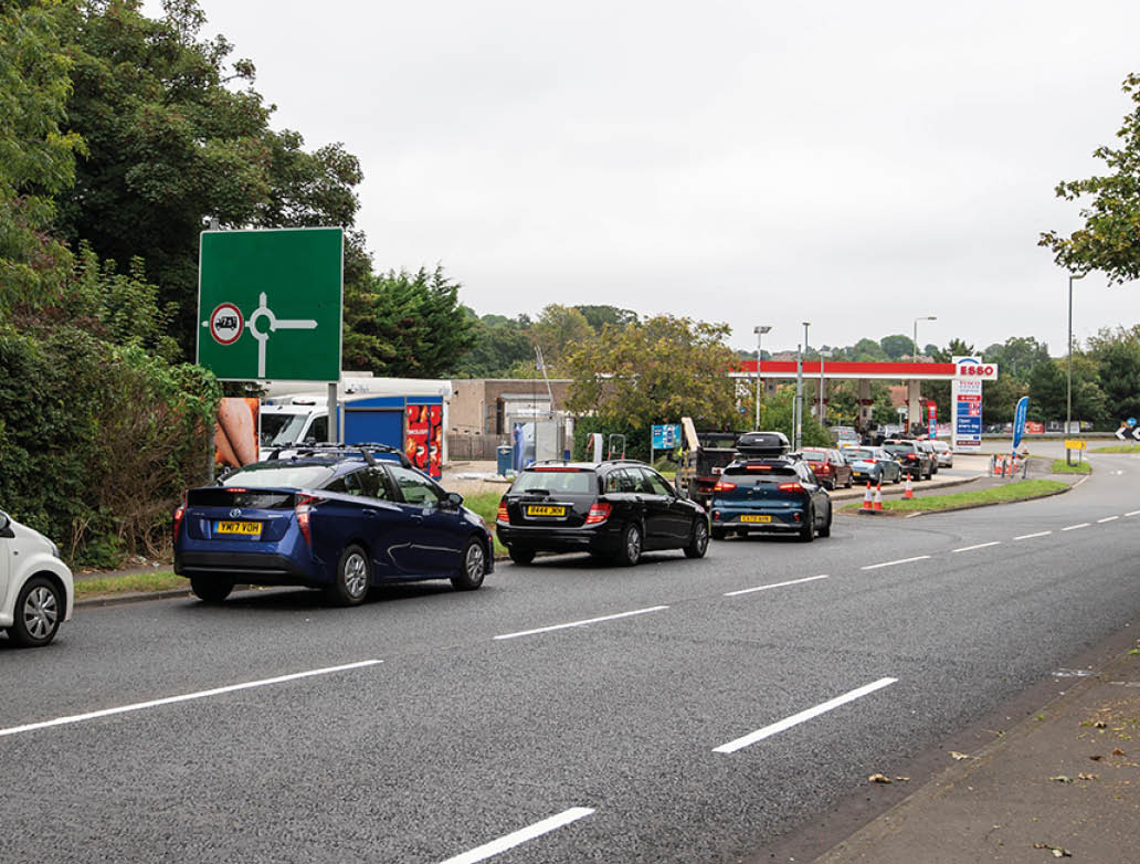 EPSOM, SURRY, UK - 2021 SEPTEMBER 25: Long tailback of vehicles queuing on the road outside an Esso filling station as UK hits fuel shortages