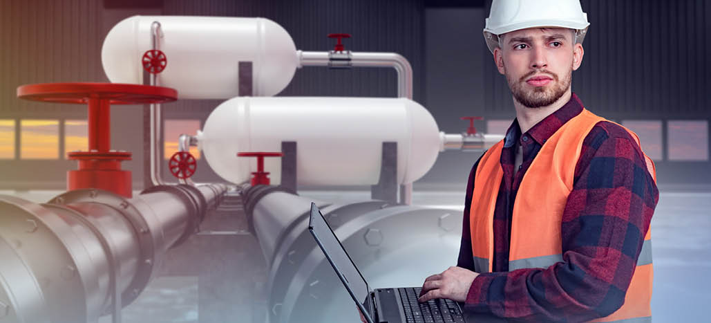 Fuel processing. Man in building with pipes. Career in oil and gas industry. Station for processing fuel and gasoline. Generation energy resources. Selective focus. Guy with laptop front fuel pipes