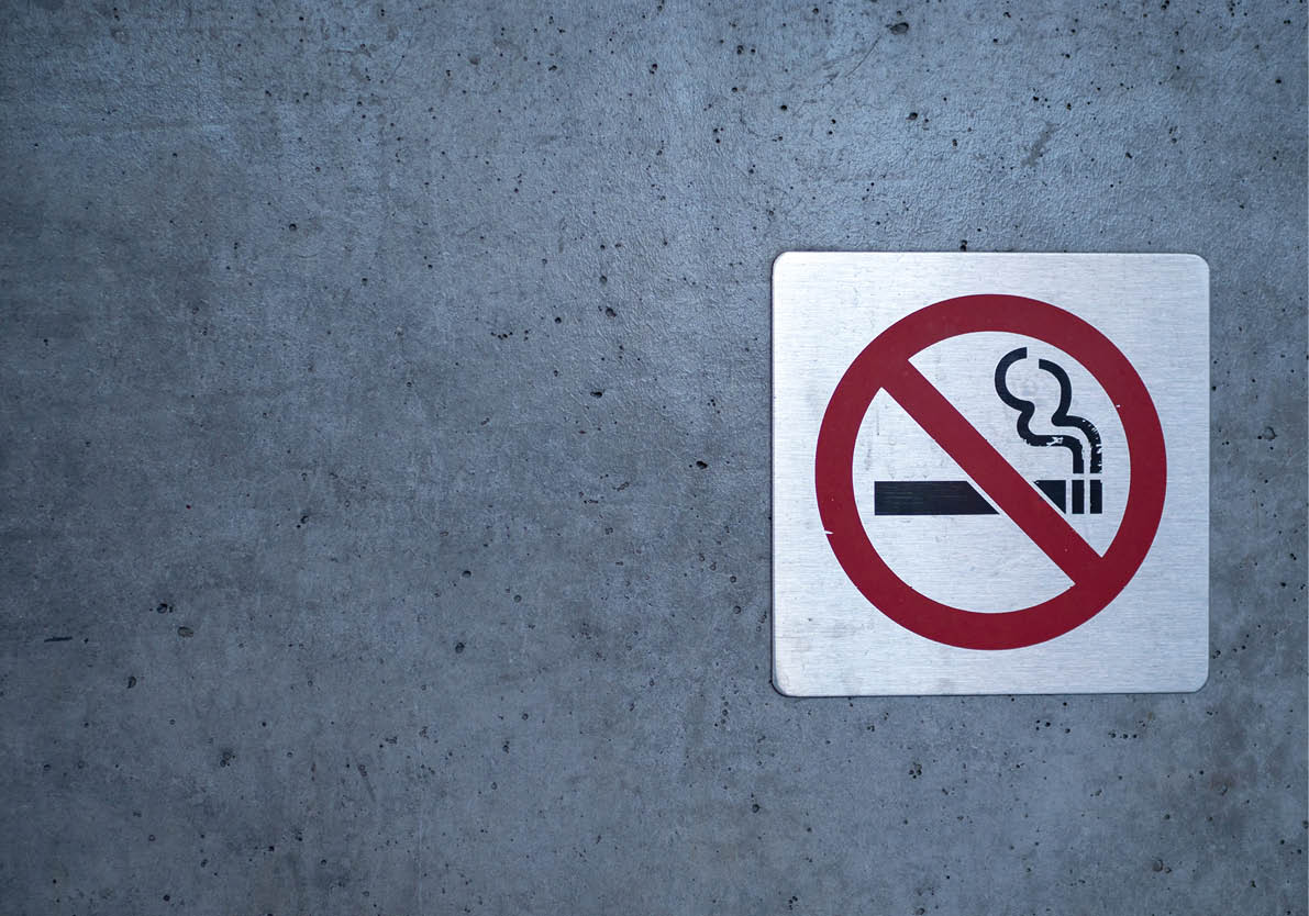 No smoking sign affixed to a wall on a building outside
