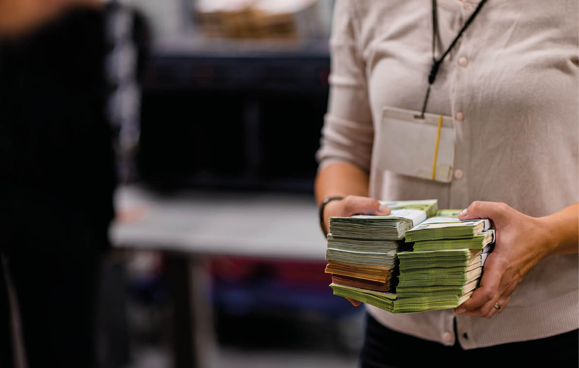 Counting person handling stacks of euro € cash sorted with bill bands at the treasury department