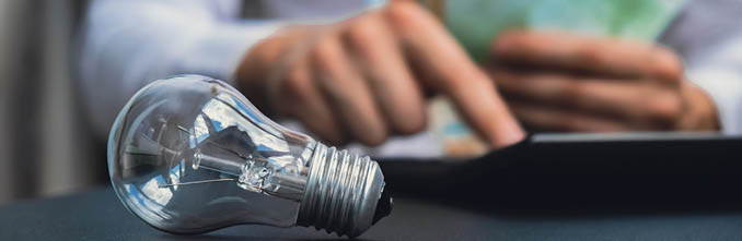 Electric light bulb. Man hands counting expenses on electricity banknotes of euro cash accounting on calculator. Close up of hands unrecognizable Businessman. High prices for energy. Save up budget investment concept Planning budget and estimating costs