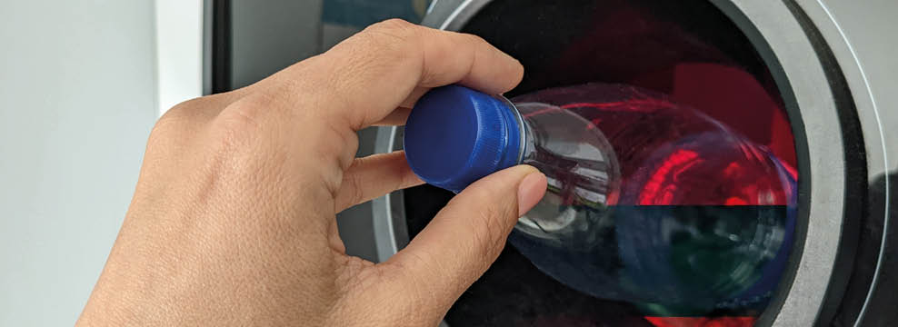 Reverse vending machine. Woman hand put empty plastic bottle in the machine. Reverse vending machine for refund and recycling metal drink cans, plastic and glass bottles