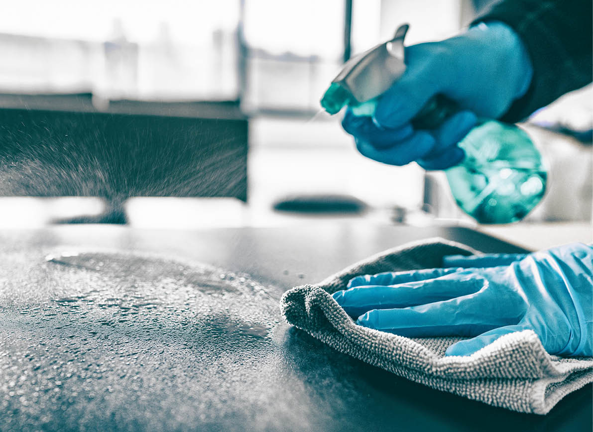 Cleaning home table sanitizing kitchen table surface with disinfectant spray bottle washing surfaces with towel and gloves. COVID-19 prevention sanitizing inside.