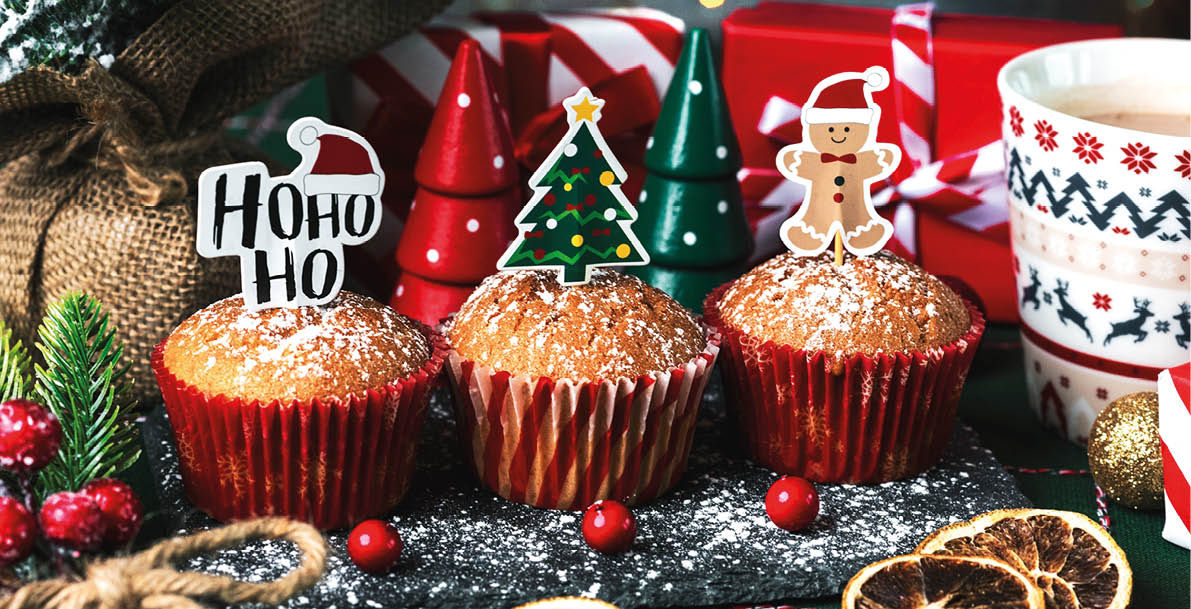 Homemade christmas muffins with fun Christmas signs and christmas decor ornaments on a tablecloth. Christmas sweet concept