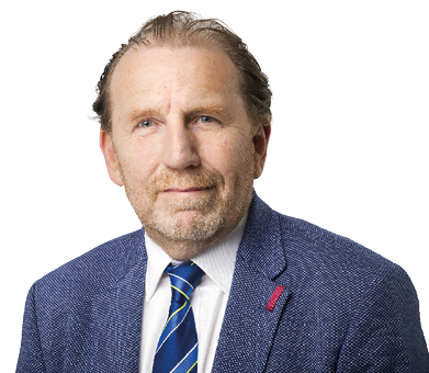 A person with short, slicked-back hair wearing a blue textured blazer, white shirt, and striped tie is looking slightly to the side against a white background. Description generated by AI