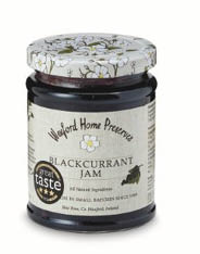 A jar of Wexford Home Preserves blackcurrant jam with a floral-patterned lid and a label featuring a flower illustration and a Great Taste award badge. Description generated by AI