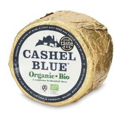 A round cheese wrapped in gold foil labeled Cashel Blue Organic Bio with a black and white circular sticker. Description generated by AI