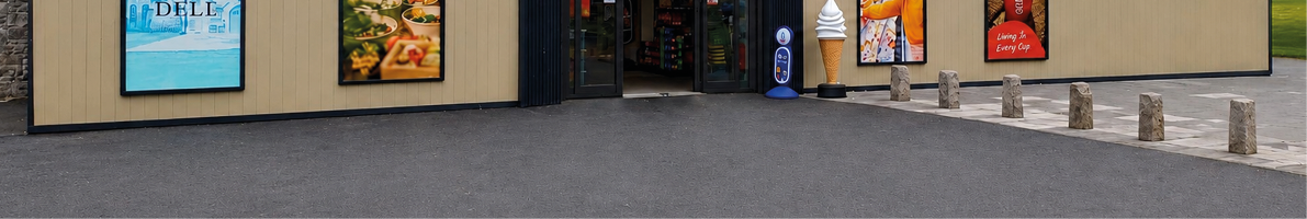 A modern convenience store named MyDaily with promotional posters for food and beverages displayed on the exterior walls and a large paved area in front. Description generated by AI