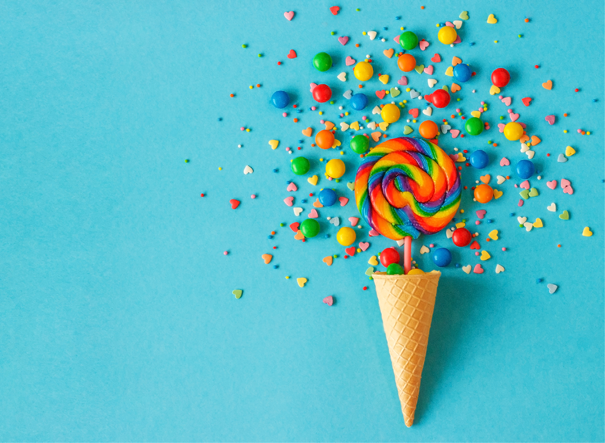 Ice cream waffle cone with colorful lollipop on stick, scattering of multicolored sweets and confectionery topping. Blue background