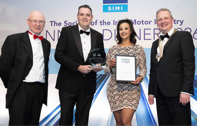 Three men and a woman pose for a photo. The woman is holding an award. AI generated content