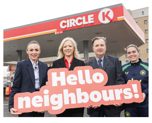Four people are standing in front of a gas station, holding up a sign that says “Hello Neighbours!" AI generated content