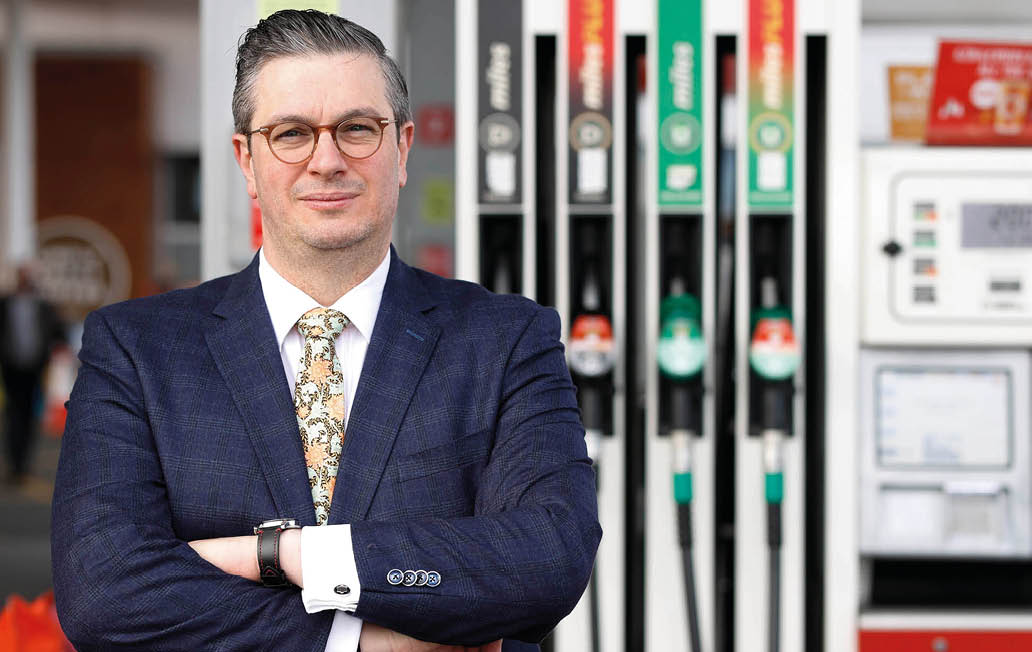 A man in a suit stands next to a gas pump. AI generated content