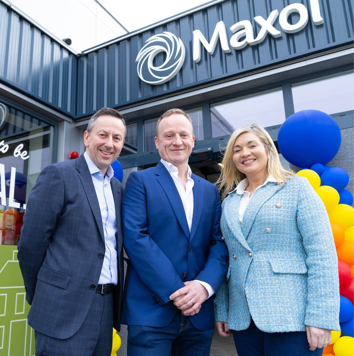 Three people pose for a photo in front of a Maxol gas station. AI generated content