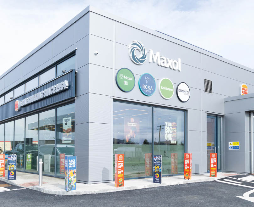 A gas station with a grey building and a blue sign. Description generated by AI