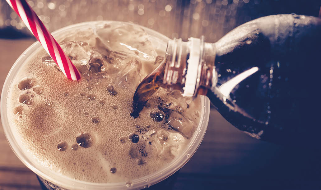 A bottle of soda with a red and white straw. Description generated by AI