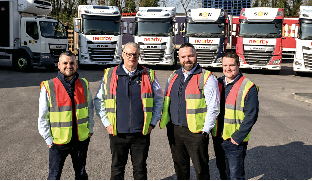 Four men wearing safety vests pose in front of a row of trucks. AI generated content