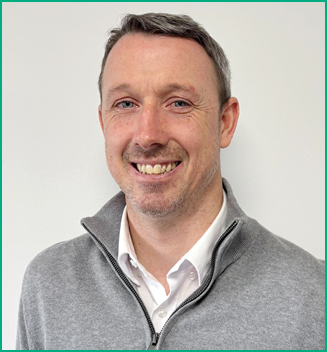 A man wearing a gray sweater with a white shirt underneath. Description generated by AI