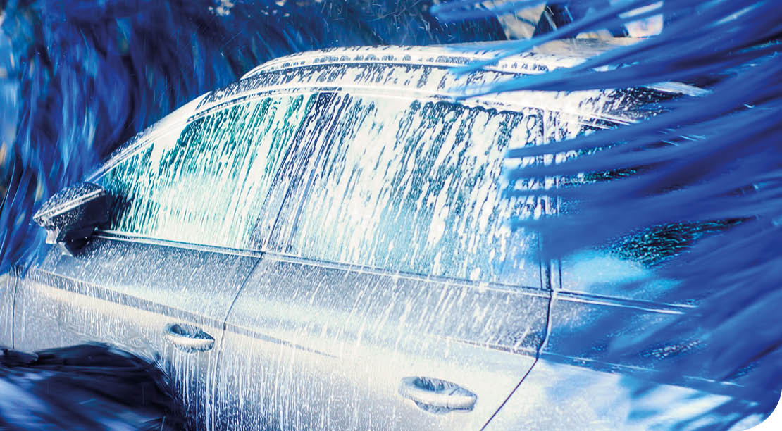 A car is being washed with a spray of blue and white water. Description generated by AI