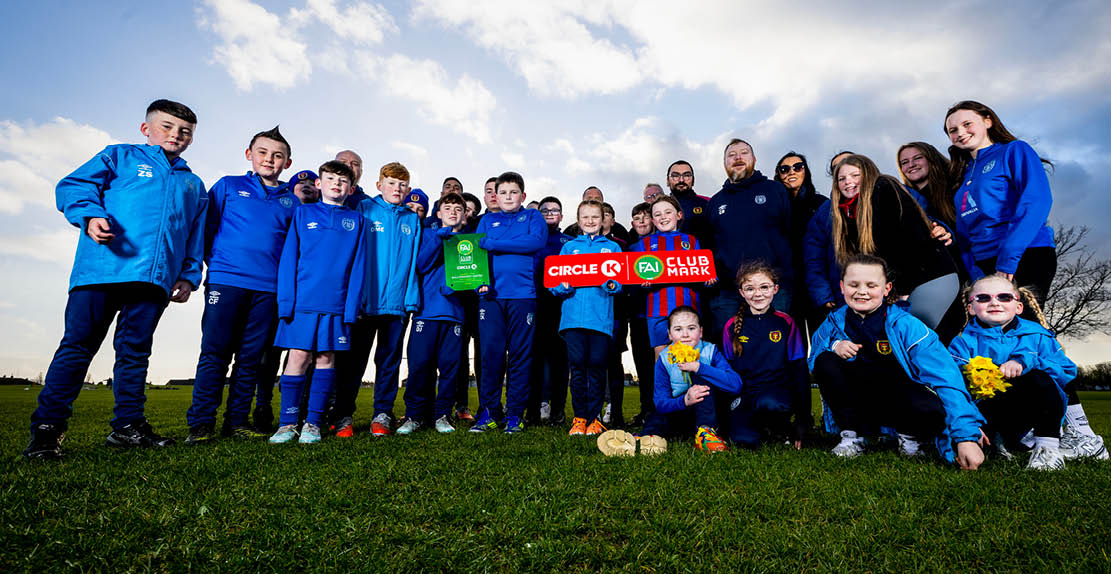 A group of people, including both adults and children, are posing for a photo on a grassy field. They are holding a frisbee, which is prominently displayed in the center of the group. The group appears to be enjoying their time together, possibly participating in a frisbee game or event. AI generated content